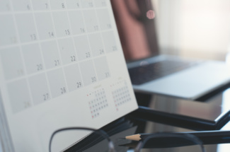 Schreibtisch mit Kalender, Brille, Stift, Laptop