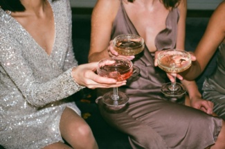 Frauen in Abendkleidern stoßen mit Weingläsern an