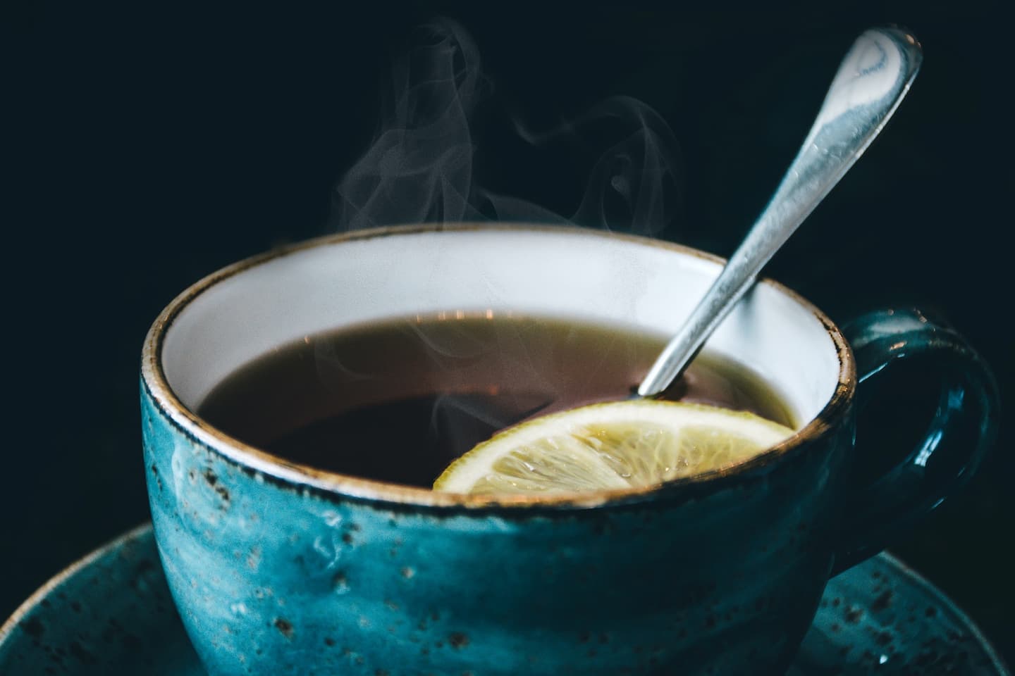 blaue Tasse mit Tee, Löffel und Zitronenscheibe
