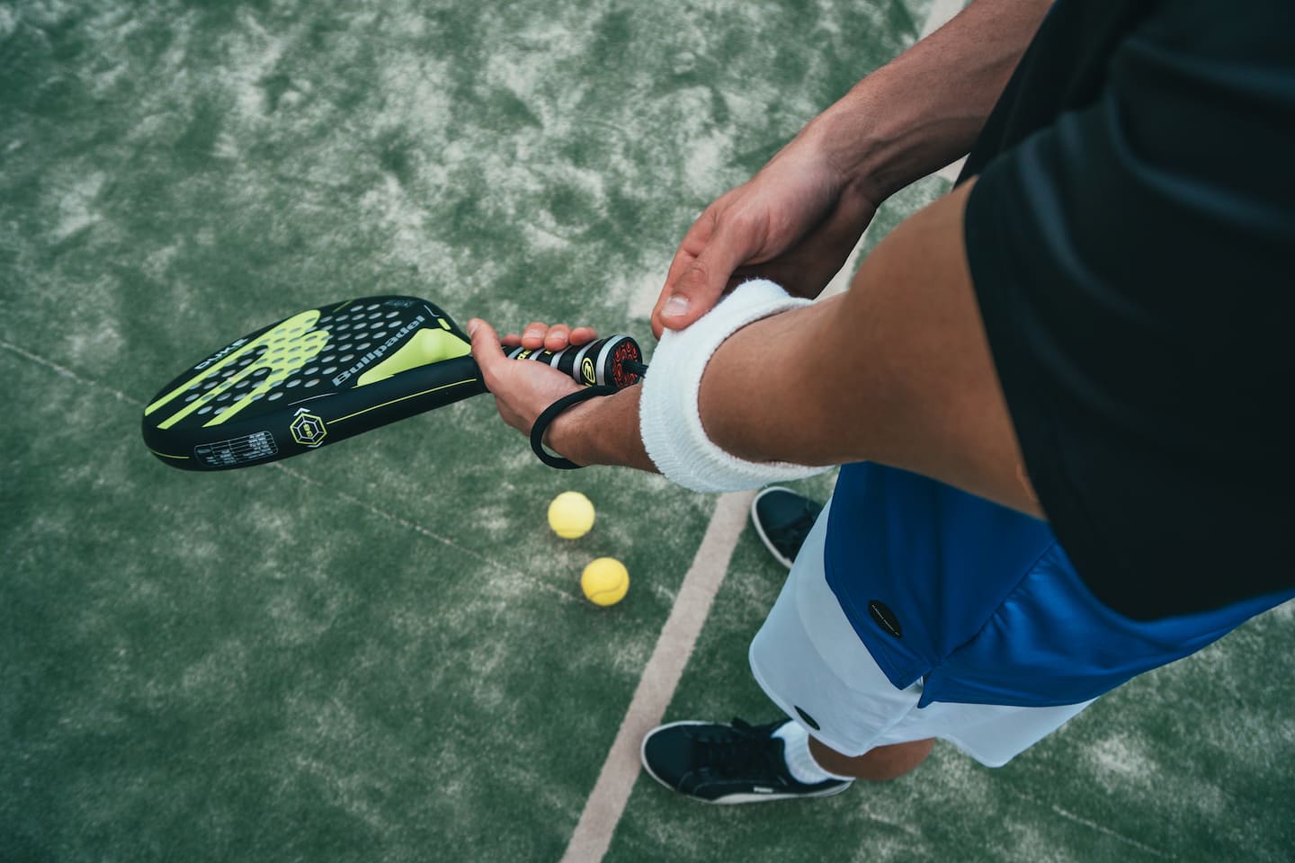 Mann hält Tennisschläger, Bälle liegen auf dem Boden