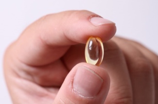 Person hält Vitamin D Tablette zwischen Daumen und Zeigefinger