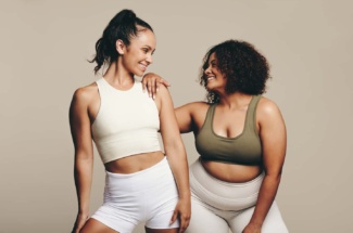 Zwei Frauen in Sport Outfits lächeln sich an