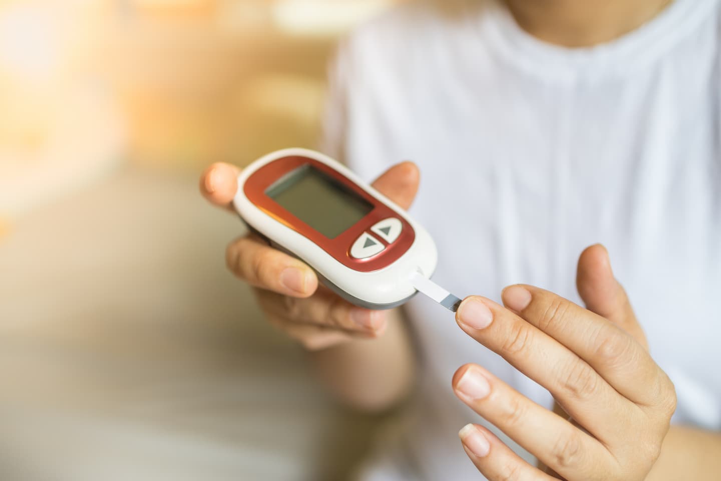 Person hält ein digitales Diabetes Messgerät an ihren Mittelfinger